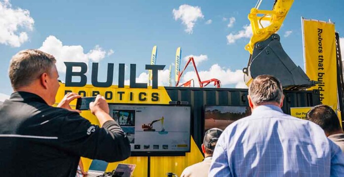 Close up of executives taking photos of robotic piling equipment outside Built Robotics' HQ