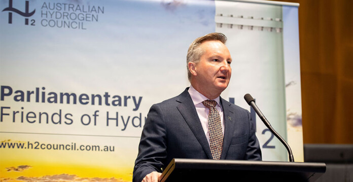 Minister for Climate Change and Energy of Australia The Hon. Chris Bowen speaks at lectern with Australian Hydrogen Council logo on banner in the background