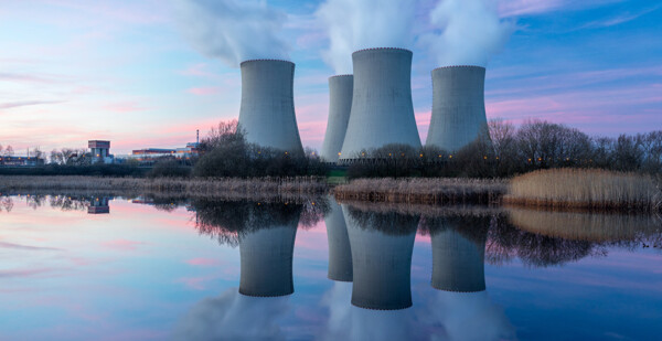 Nuclear power plant chimneys reflected in lake at sunset (debate)