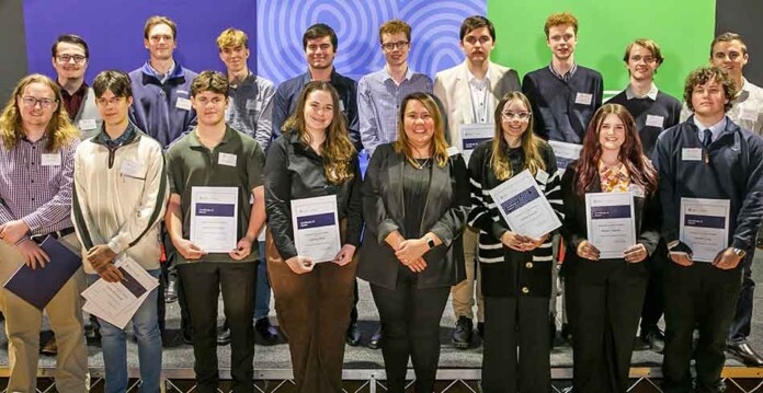 Twenty university scholarship recipients pose with framed certificates