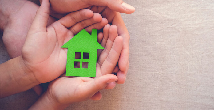 Adult and child hold green house cutout in their cupped hands