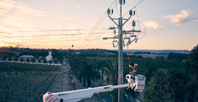 SA Power Networks worker uses crane lift to work on Stobie power pole at dusk